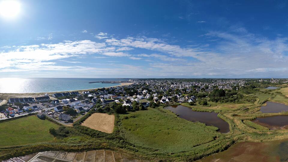 A coastal town with a marina, green fields, and a large body of water.