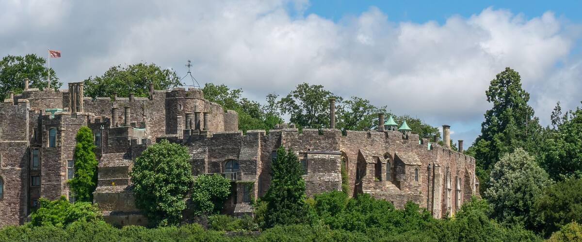 A historic stone castle surrounded by lush greenery and trees.
