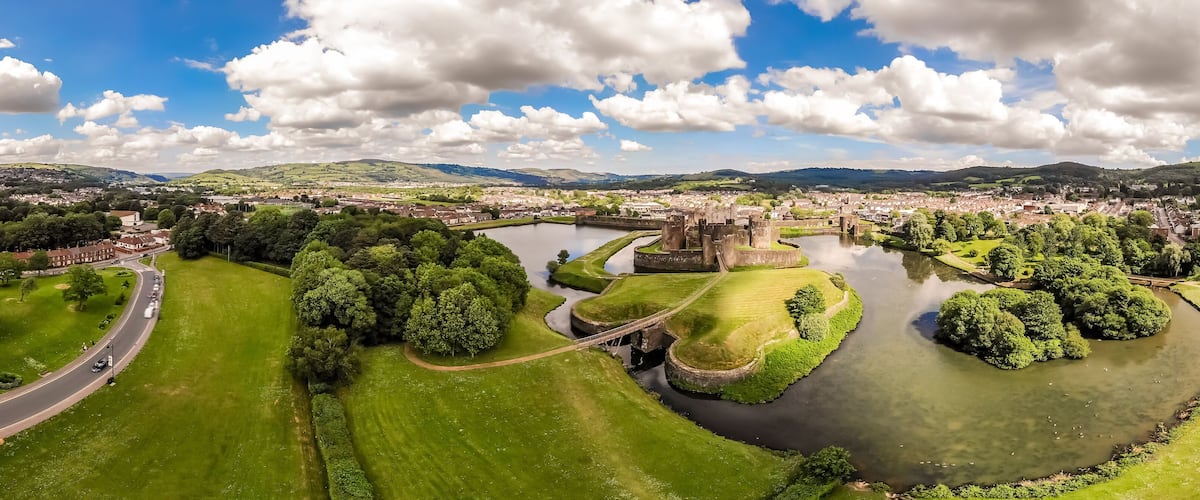 A panoramic view of a town with a river, green parks, and historic buildings.
