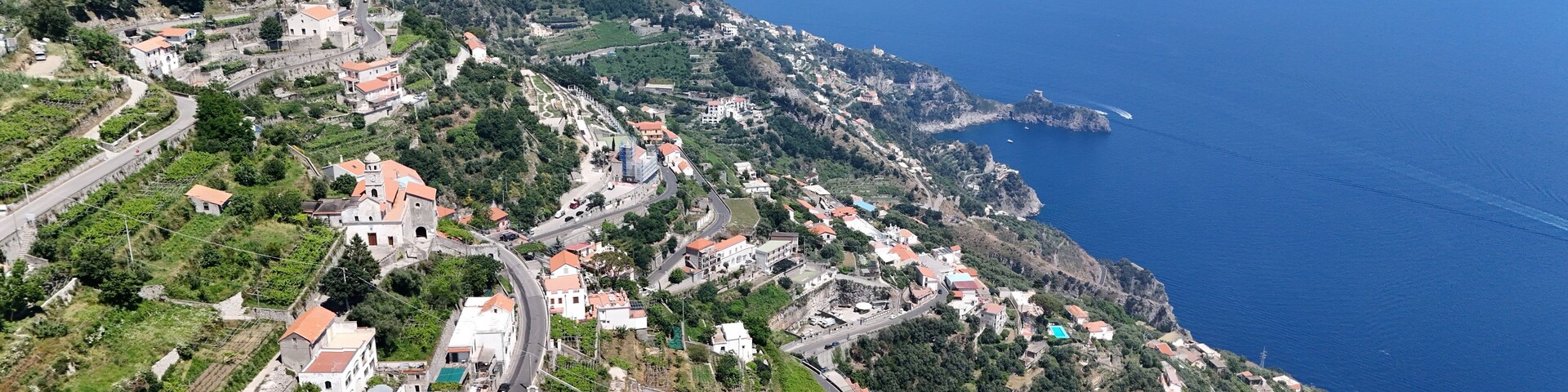 Un pueblo costero con casas escalonadas, caminos serpenteantes y una ladera pronunciada.