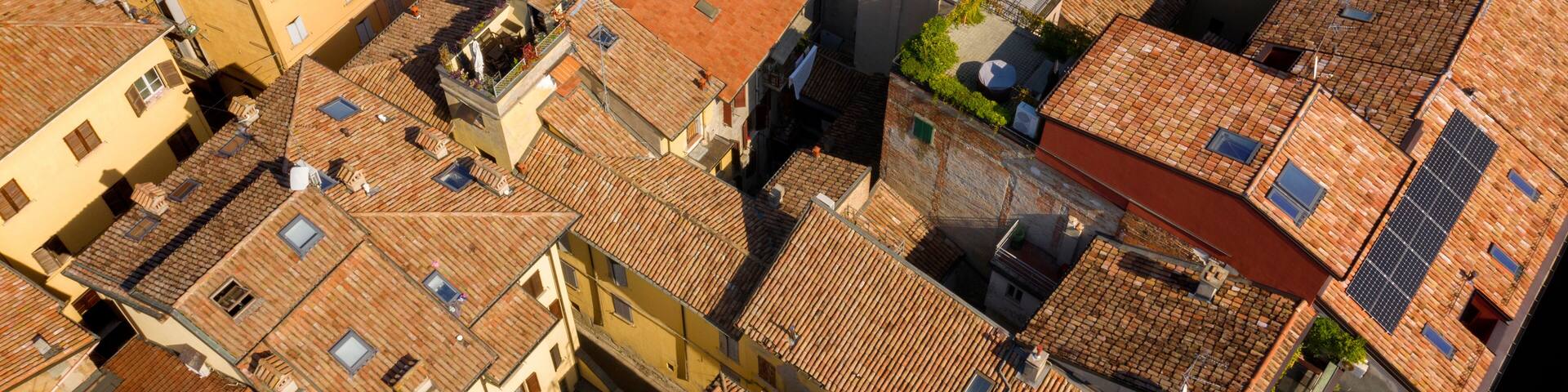 Aerial view of the sloping roofs of the houses in the historic center of Reggio Emilia, Italy. The orange color of traditional roofs predominates.