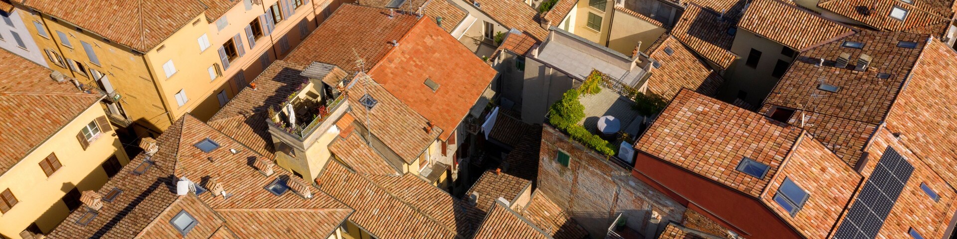 Aerial view of the sloping roofs of the houses in the historic center of Reggio Emilia, Italy. The orange color of traditional roofs predominates.