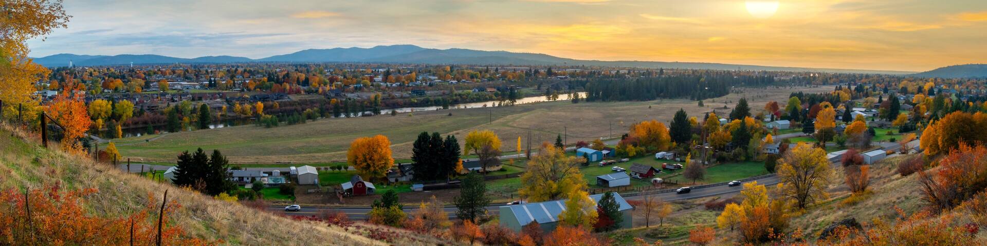 Panoramic hillside view over Spokane Valley looking towards downtown Spokane, Washington, as the sun sets on an Autumn day with fall colors.