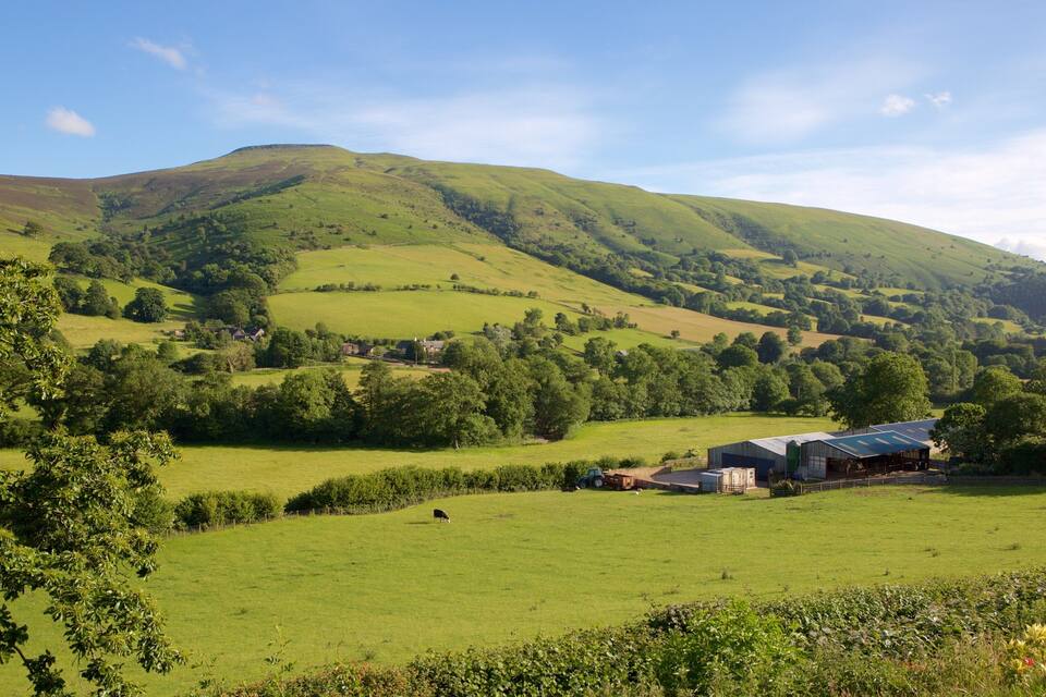Rolling hills, green fields, a barn, and a tractor.