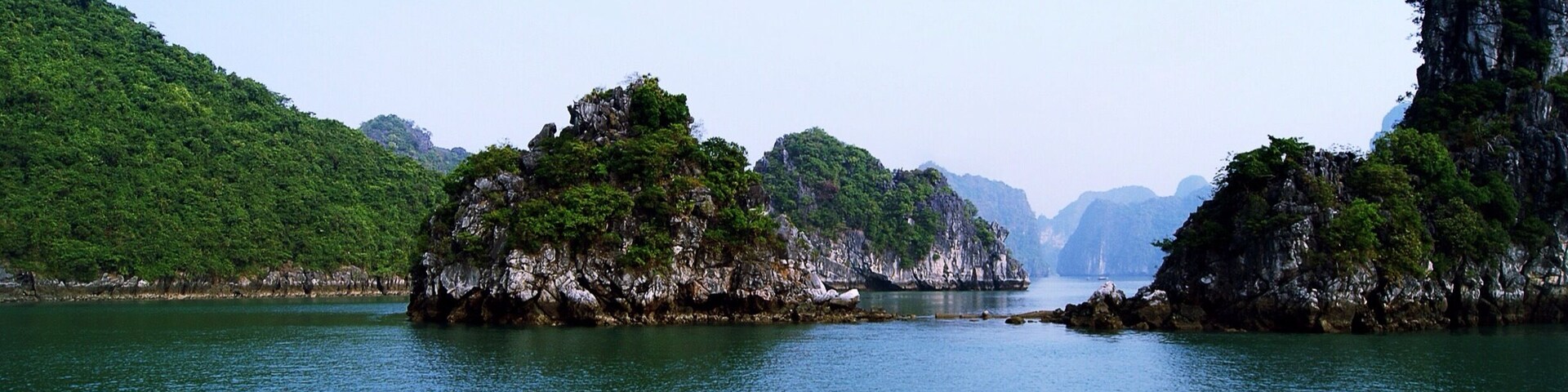 Una bahía tranquila con islas rocosas y colinas verdes y exuberantes.
