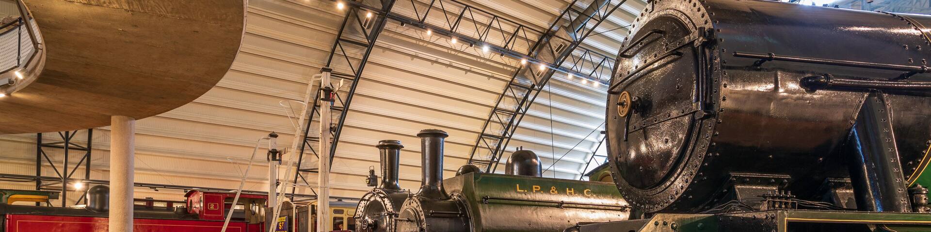 A steam locomotive in a museum with other vintage trains.