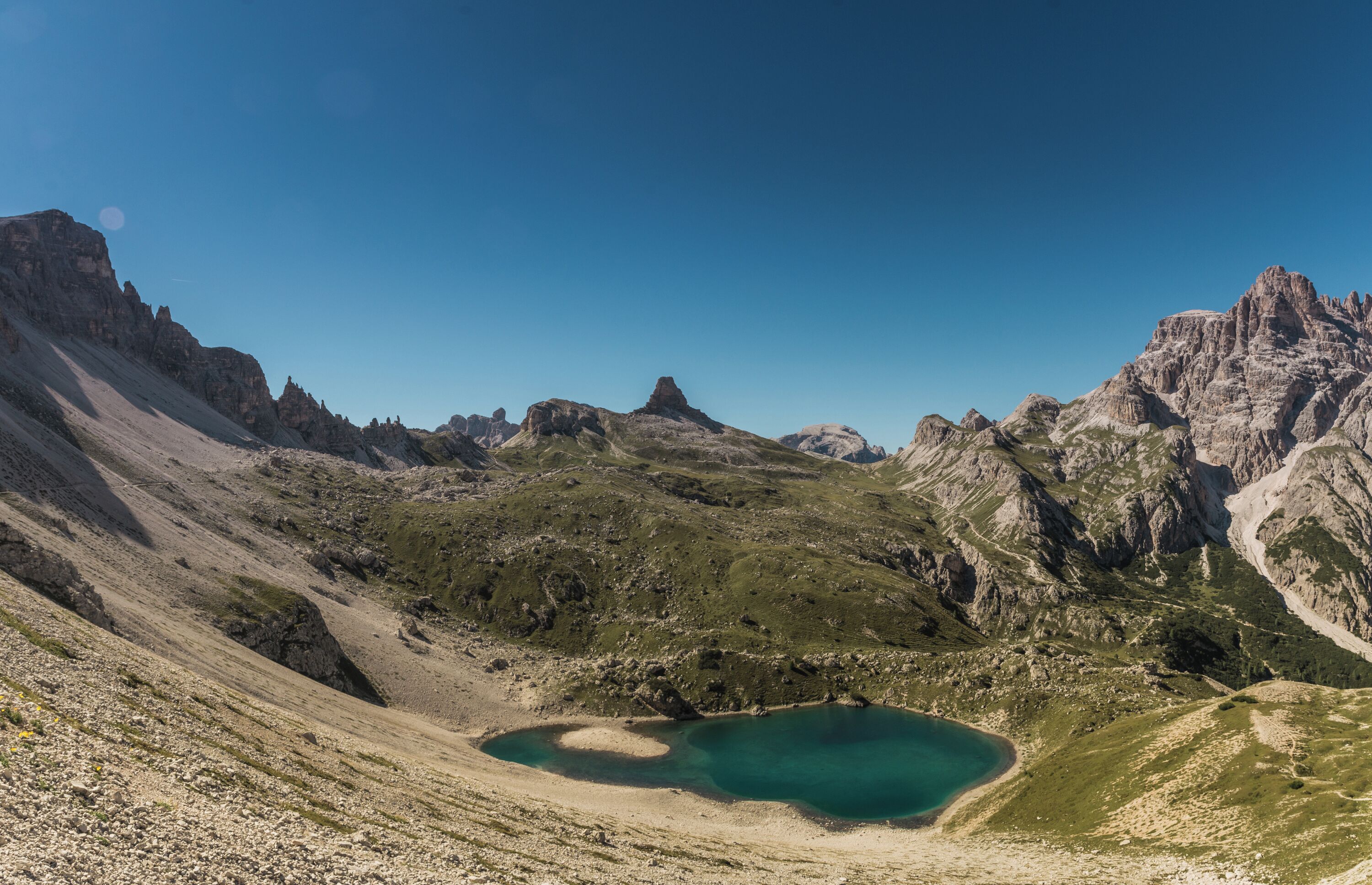 A mountainous landscape with a turquoise lake surrounded by rocky terrain and sparse vegetation.
