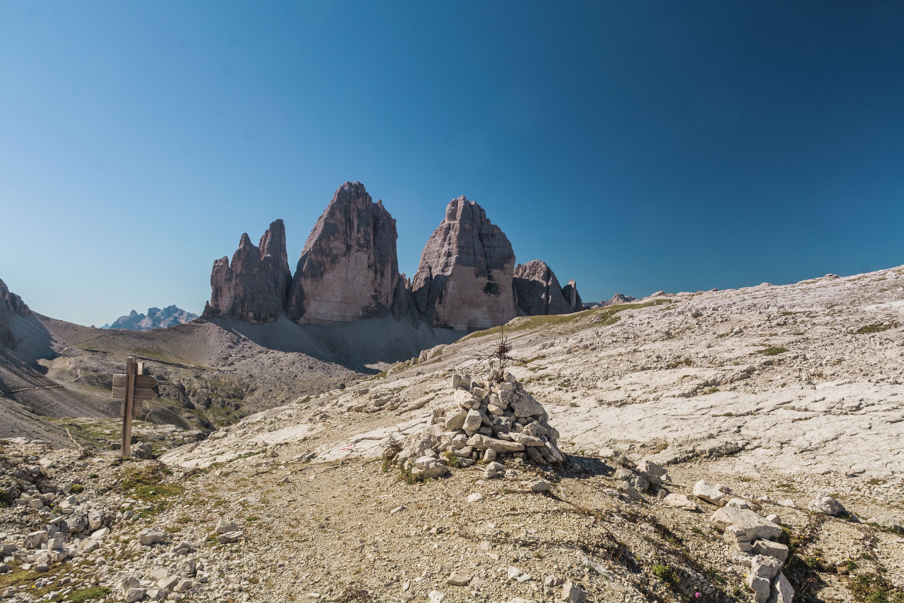 A rocky mountain landscape with a cairn and a wooden sign.