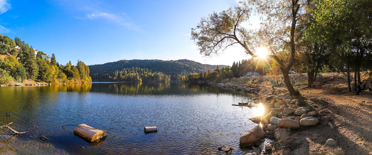 Ein ruhiger See, umgeben von Bäumen und Hügeln.