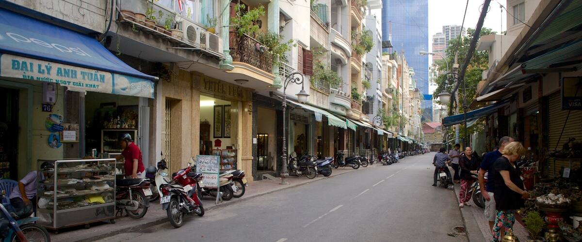 A narrow street lined with shops and motorcycles parked along the sides.