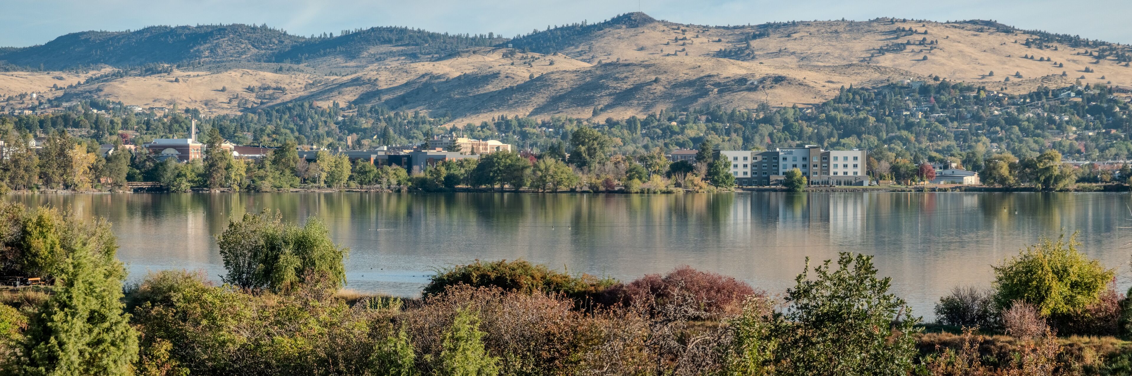 A lake with buildings and hills in the background.