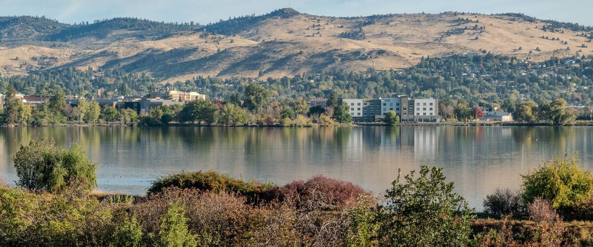 A lake with buildings and hills in the background.