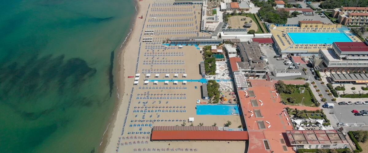 An aerial view of a beach with rows of sun loungers and a swimming pool.