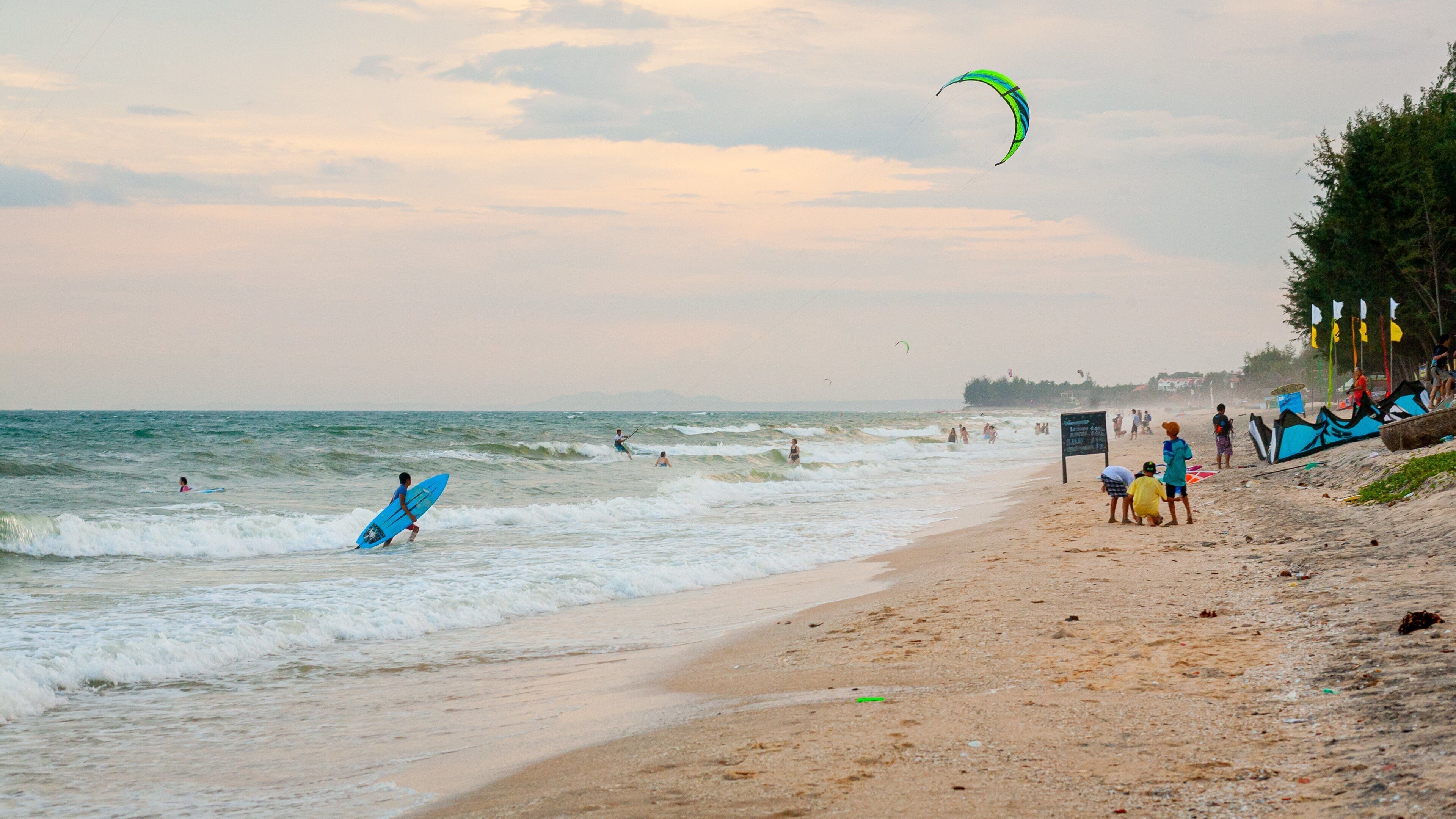 Una playa con olas, gente y una cometa.