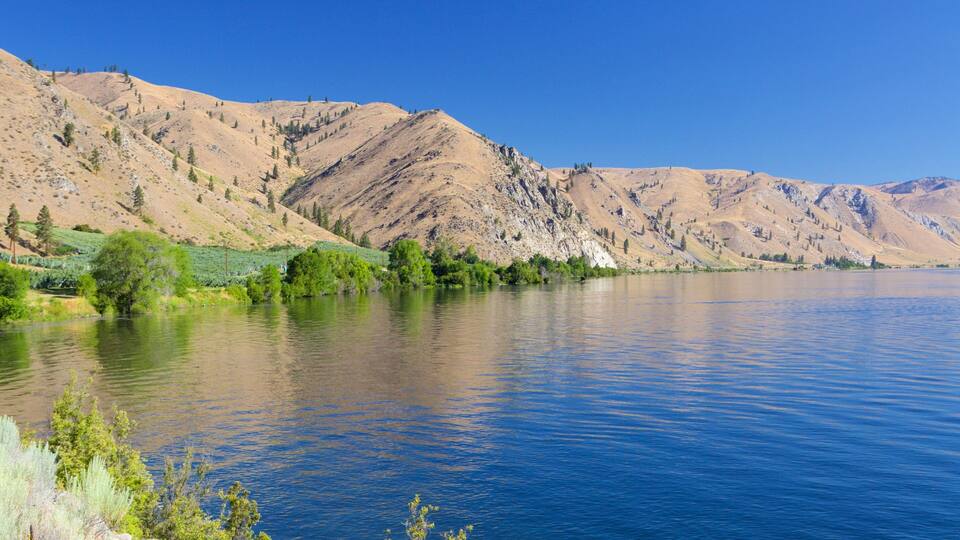 A calm lake with mountains in the background.