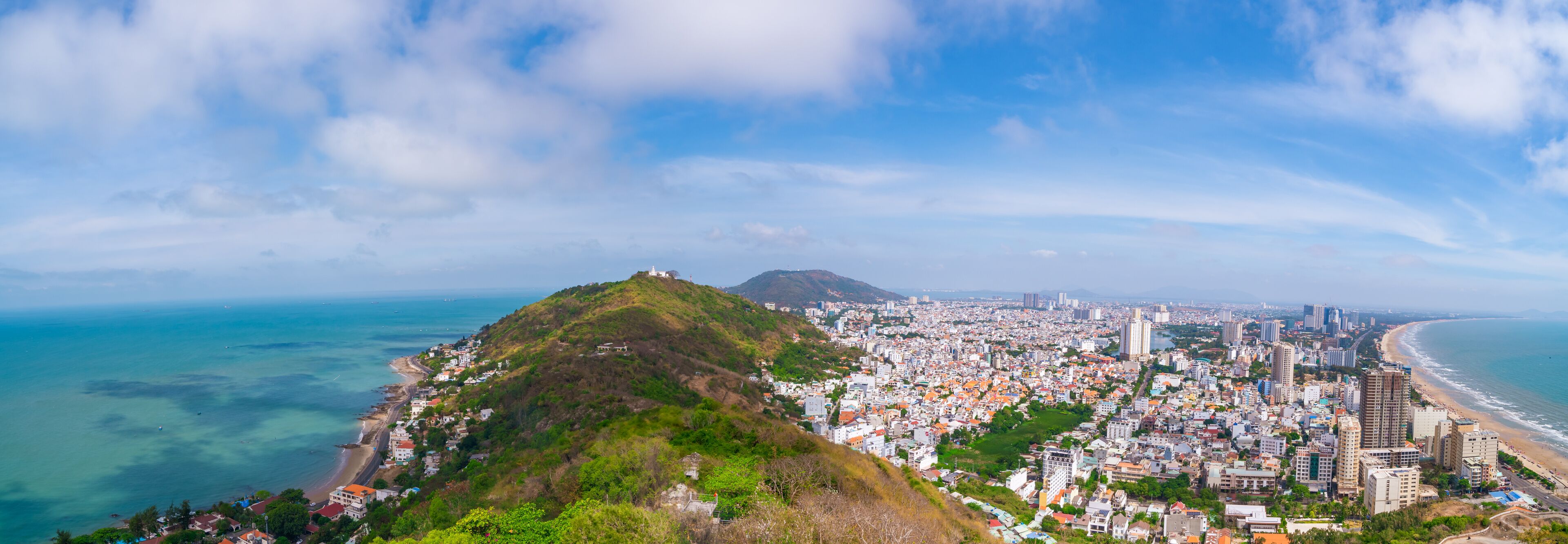 A coastal city with a prominent hill, a beach, and a dense urban area.