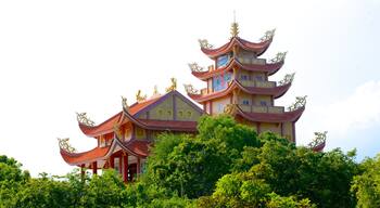 A multi-tiered pagoda with ornate golden decorations and a red roof, surrounded by lush greenery.