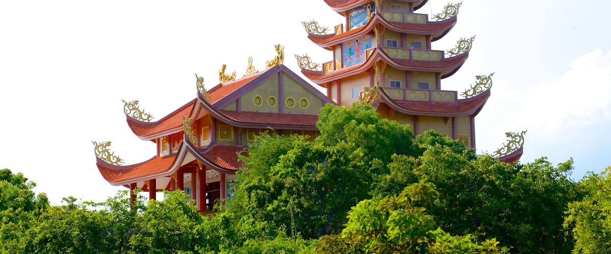 A multi-tiered pagoda with ornate golden decorations and a red roof, surrounded by lush greenery.