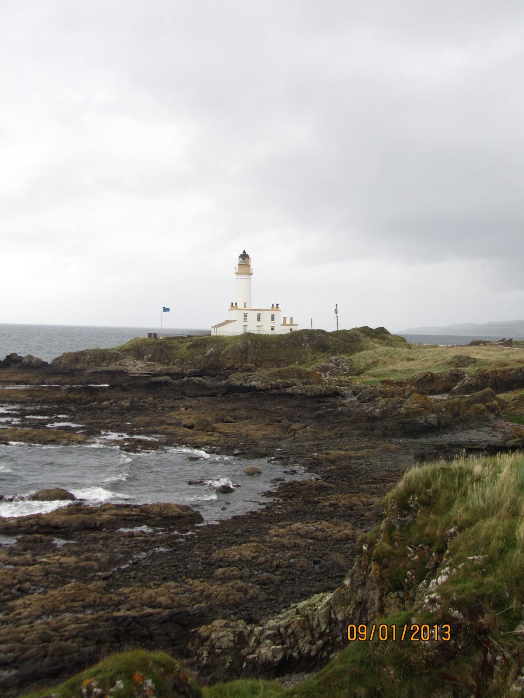 Un faro en una costa rocosa bajo un cielo nublado.