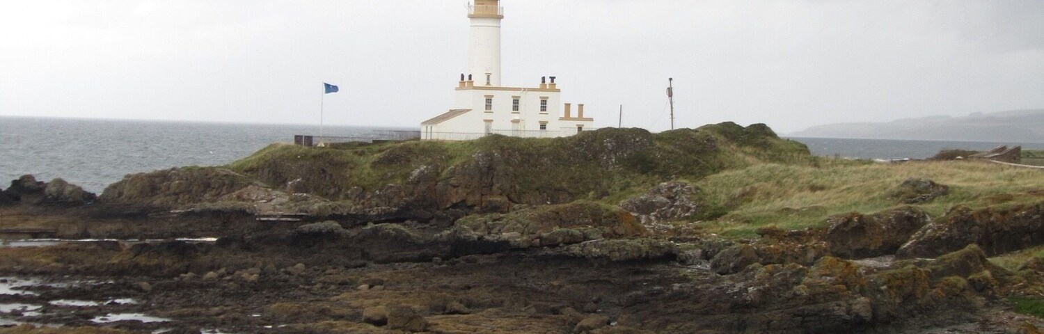 Un faro en una costa rocosa bajo un cielo nublado.