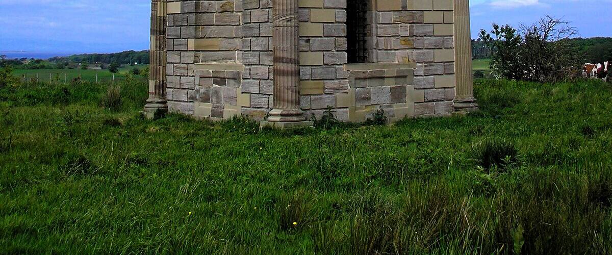 A stone structure with a pointed roof and two small domes on either side.