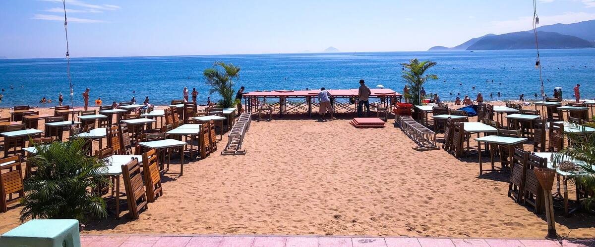 A beachside restaurant with tables and chairs facing the ocean.