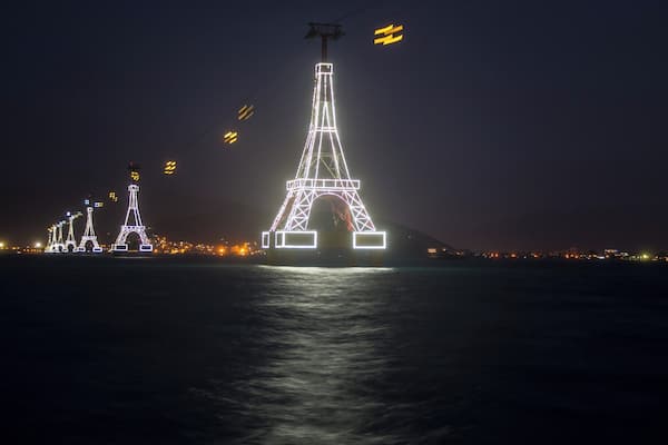 A nighttime view of the Eiffel Tower and other illuminated structures by the water.