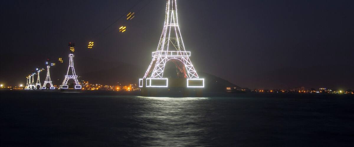 A nighttime view of the Eiffel Tower and other illuminated structures by the water.