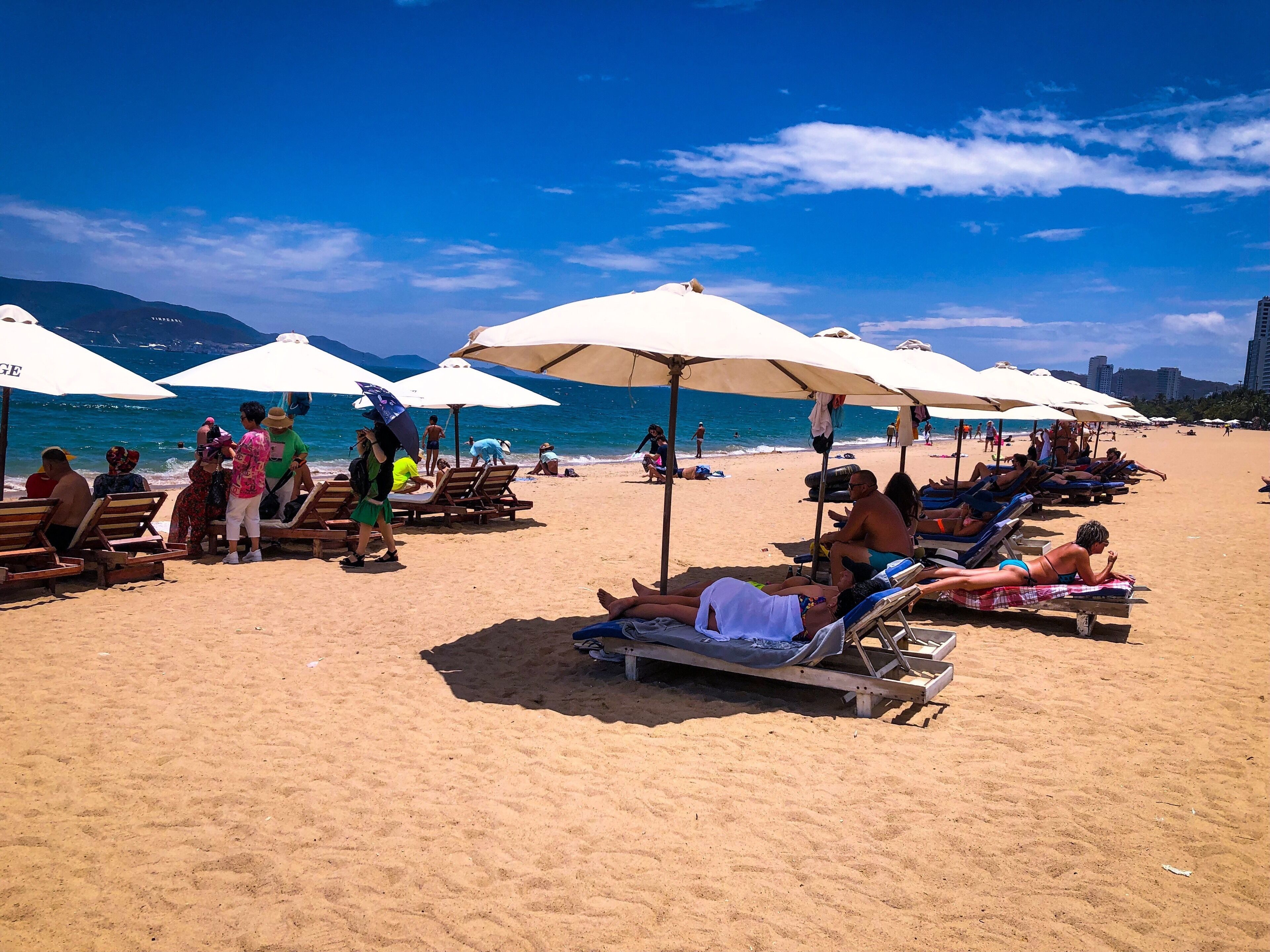 A beach with sun loungers and umbrellas under a clear blue sky.