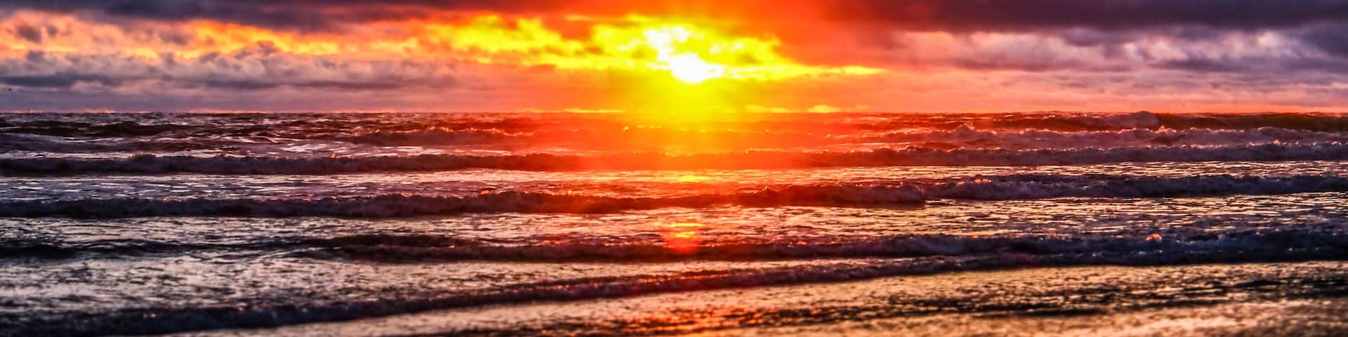A sunset over the ocean with waves reflecting the sun's light.