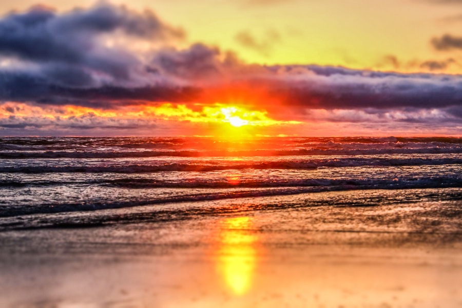 Un atardecer sobre el océano con olas que reflejan la luz del sol.