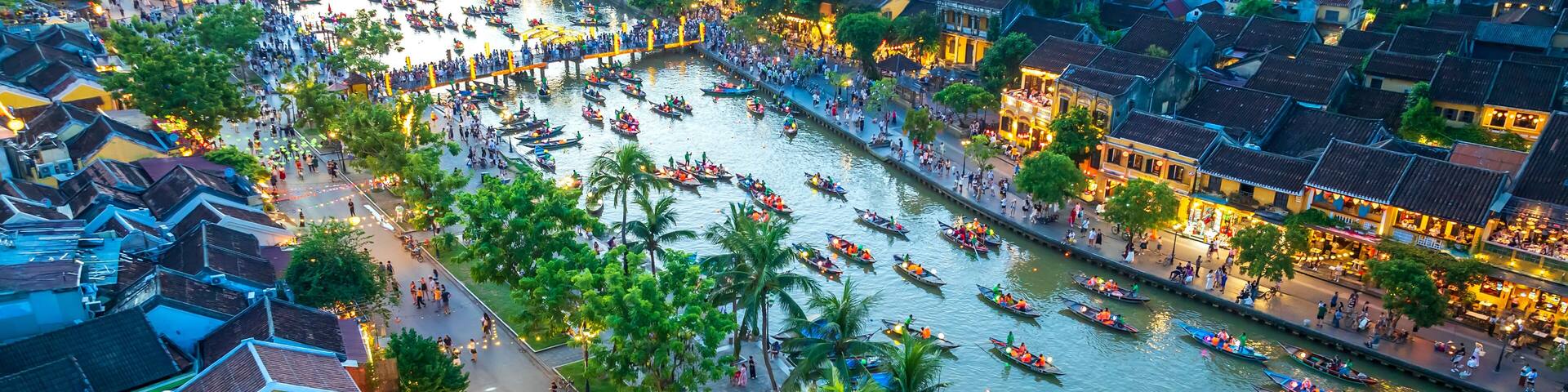 A river with boats, a crowd, and traditional buildings along the banks.