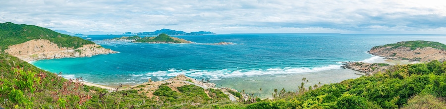 Secluded tropical coast line turquoise transparent water palm trees, undeveloped bay Quy Nhon Nha Trang, Vietnam central coast travel destination, no people clear blue sky, expansive view