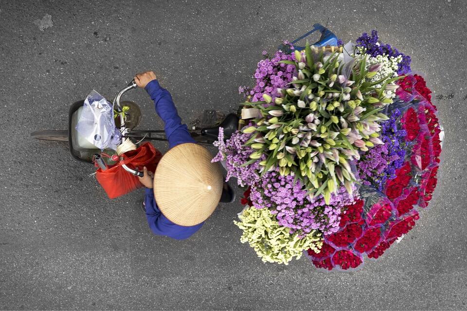 Una persona amb una bicicleta i un gran ram de flors al terra.