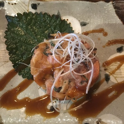 A plate with a seafood dish, garnished with a leaf and drizzled with sauce.