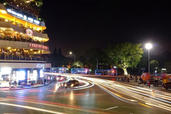 A busy intersection with a brightly lit restaurant named 'Legend Beer' and a store named 'Aldo' on the left.