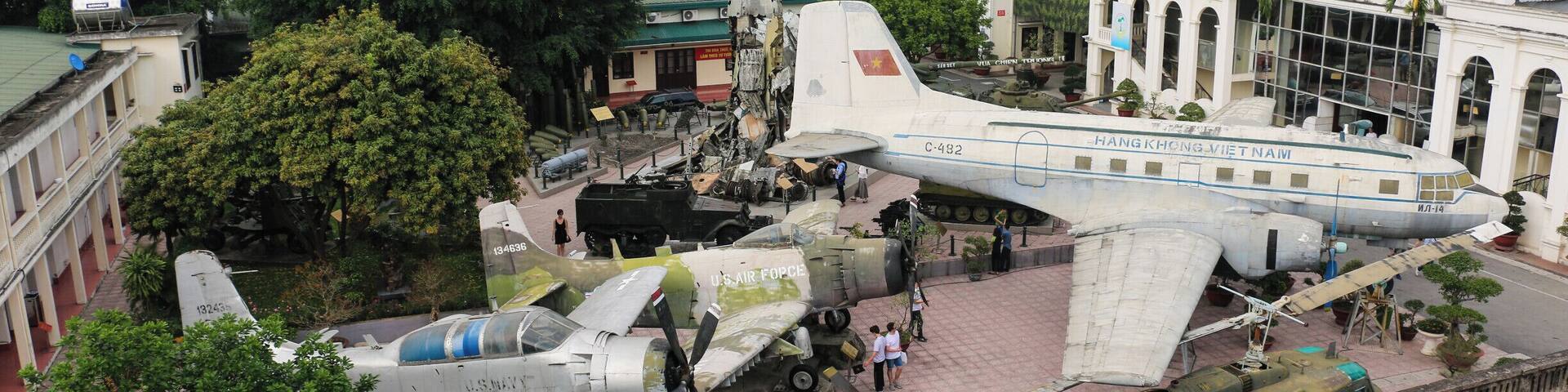 A historical aircraft on display with a backdrop of trees and buildings.