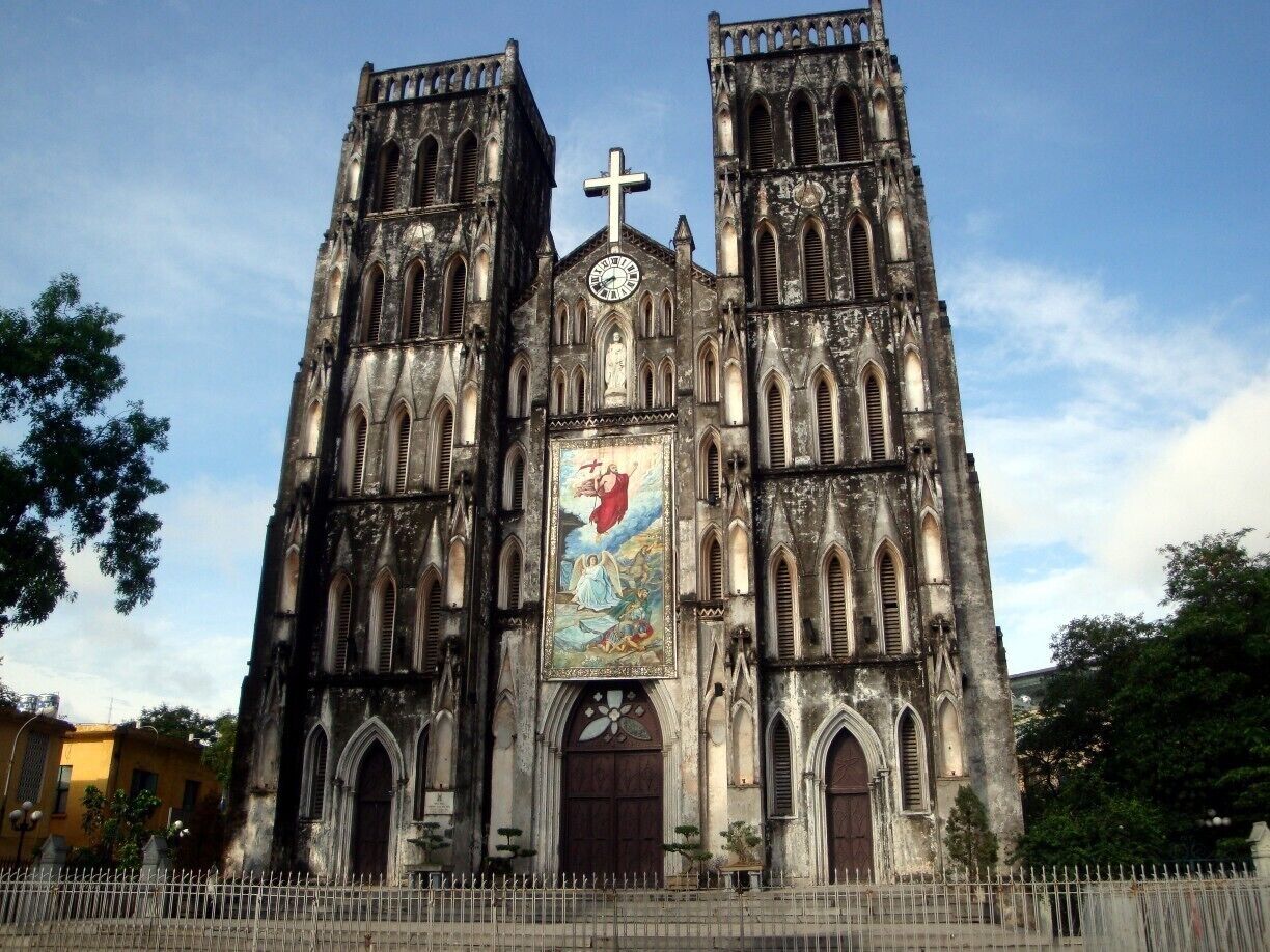A Gothic-style cathedral with two towers, a large central rose window, and a cross at the top.
