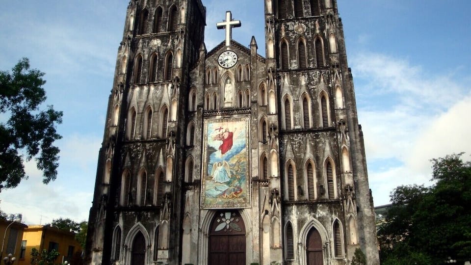 A Gothic-style cathedral with two towers, a large central rose window, and a cross at the top.