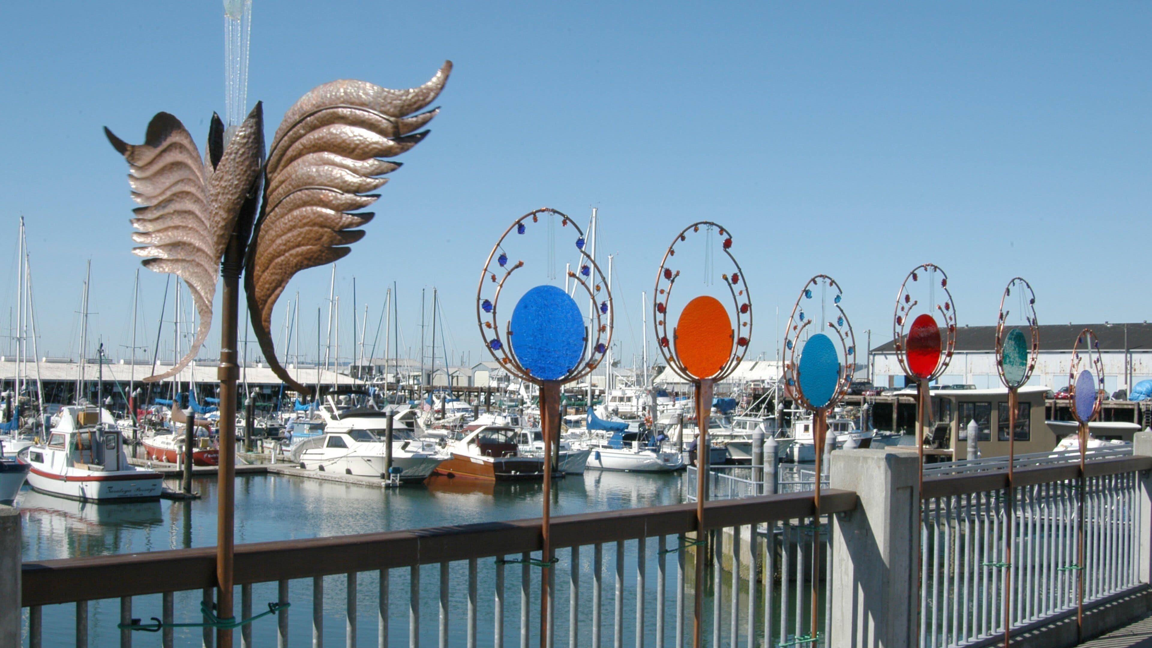 A marina with boats and decorative metal sculptures.