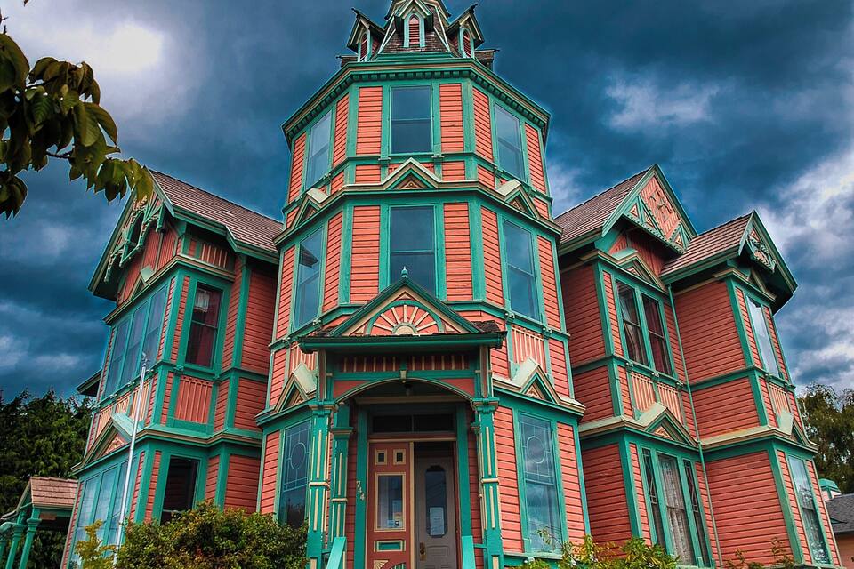 A large, colorful Victorian-style house with green trim and multiple windows.