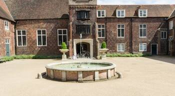 A historic building with a clock tower, a courtyard with a fountain, and a brick facade.
