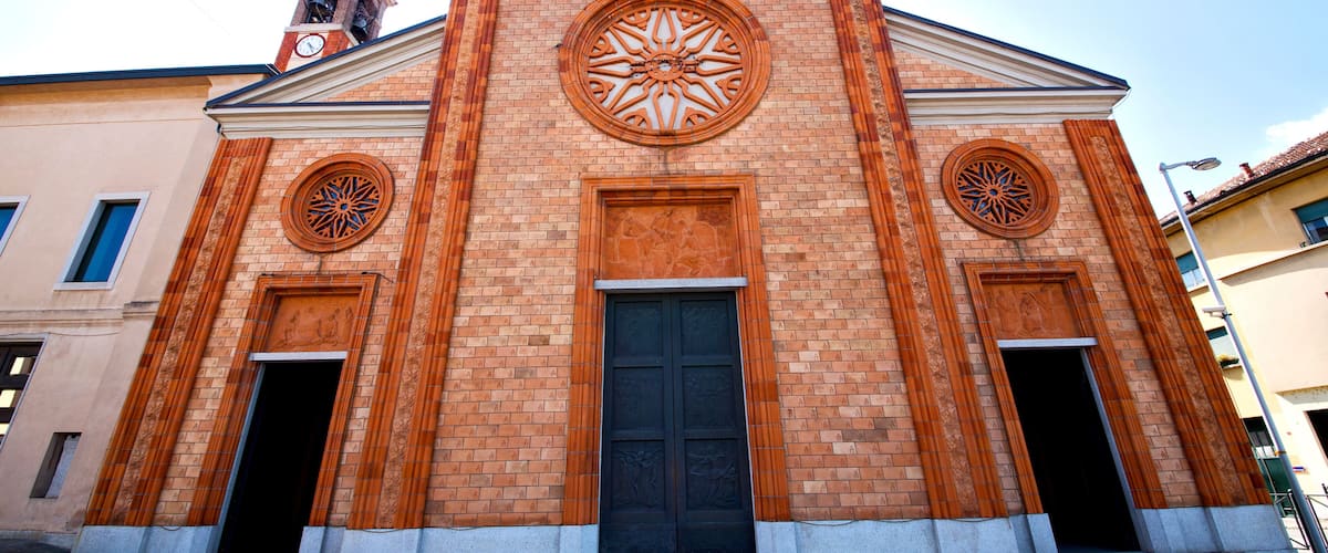 A church with a brick facade, two large circular windows, and a central door.
