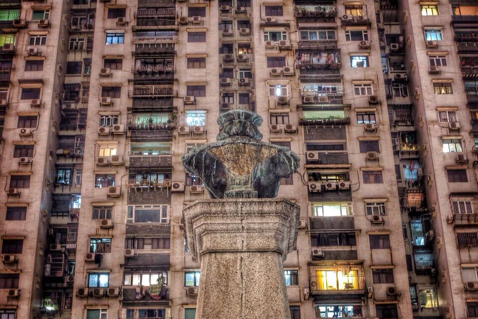 A statue in front of a tall residential building with many windows.