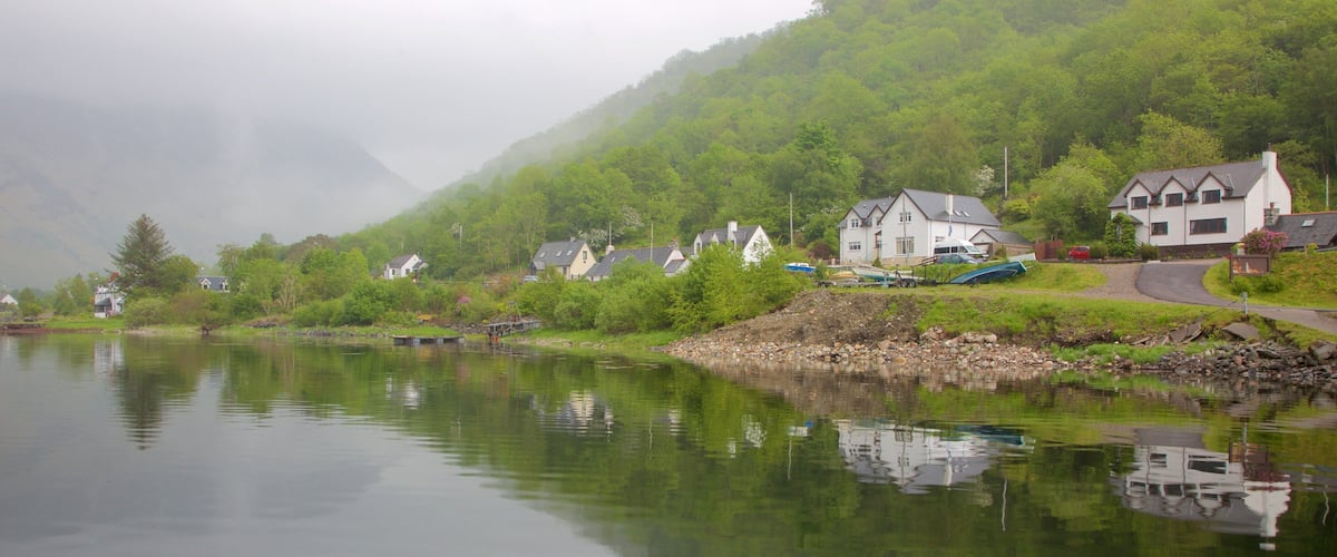 A calm lake with houses and a mountain in the background.