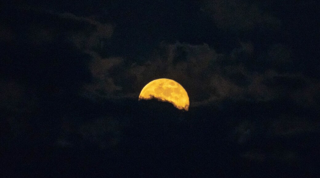 Full moon rising through the clouds over the Oregon Cascades.