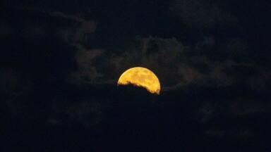 Full moon rising through the clouds over the Oregon Cascades.