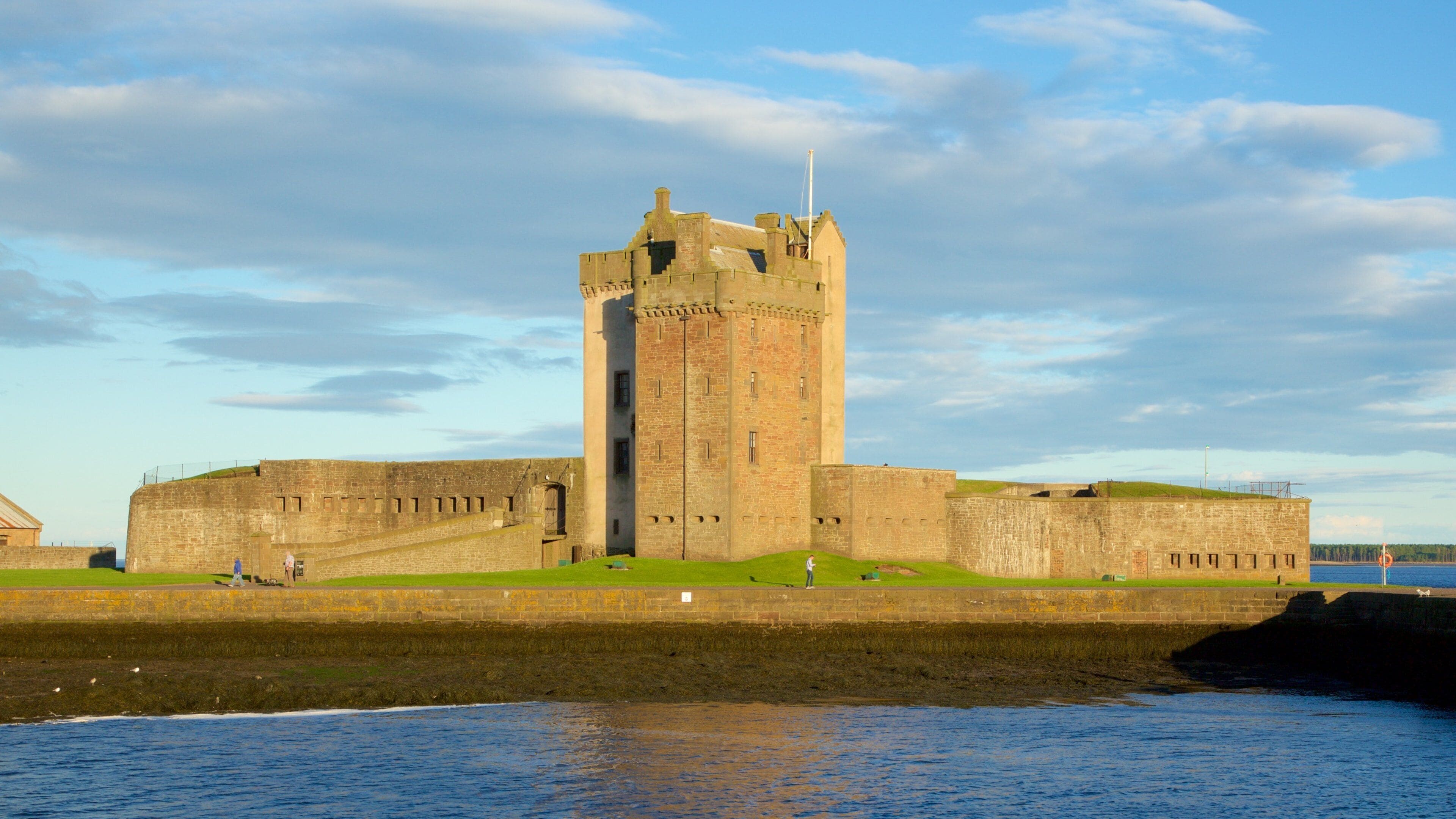 A historic castle with a prominent tower, situated by a body of water.