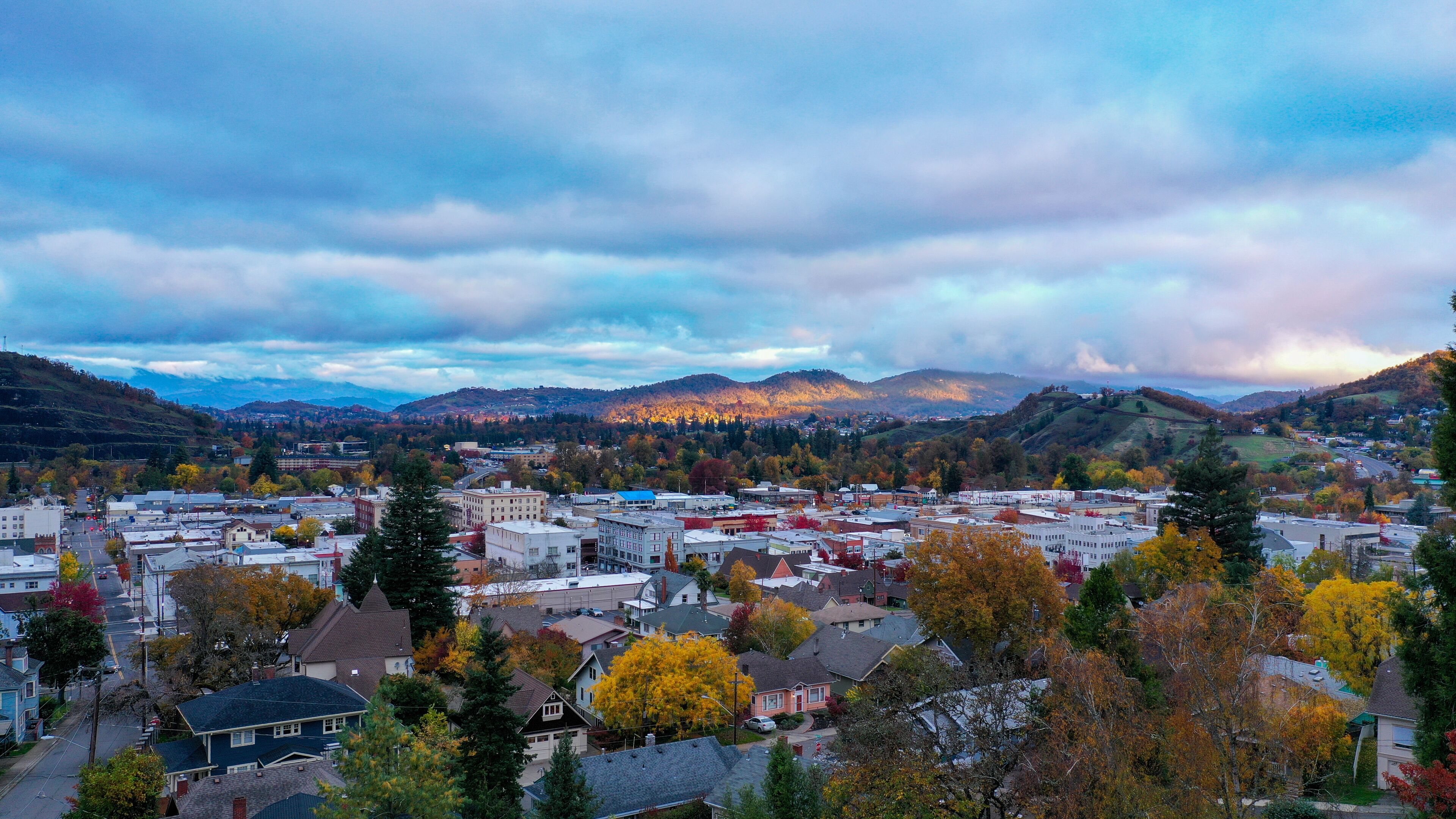 A town nestled in a valley with autumn foliage, surrounded by hills and mountains.