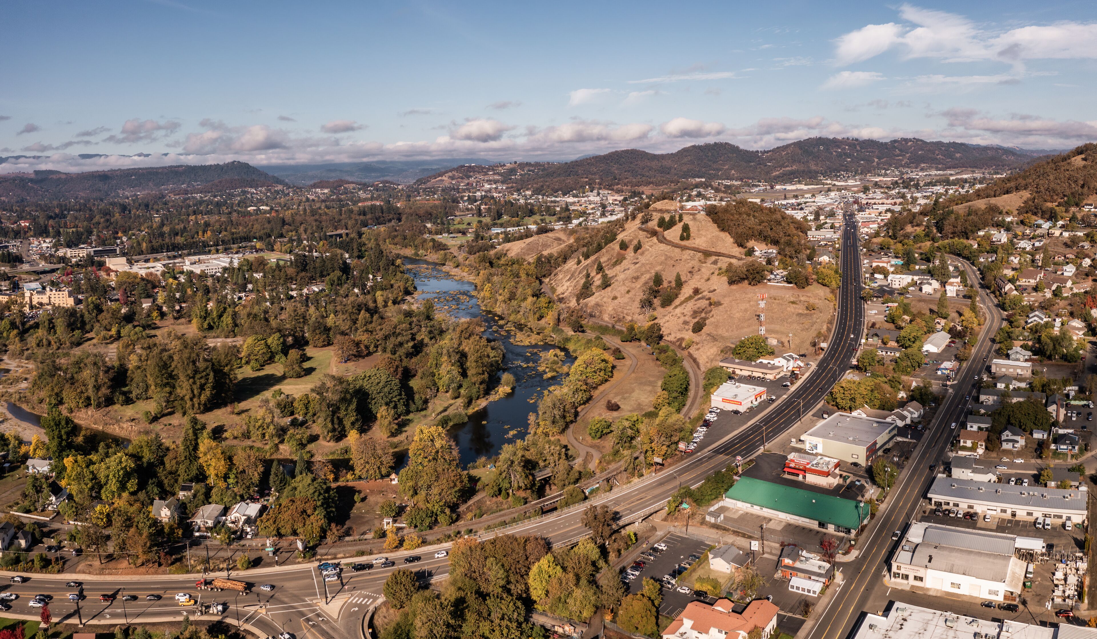 A town with a river, a highway, and surrounding hills.